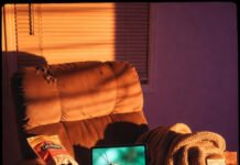 Match Updates Today: Live Cricket Action from Around the World Dusty orange-purple scene: tired recliner, gas-station jerky, cricket macro on screen, single cowboy boot beside it.